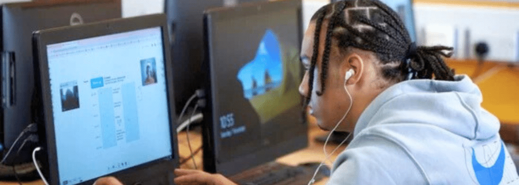 A picture of a pupil looking at a computer monitor during an Action Tutoring session. The pupil is wearing earphones and using the Action Tutoring online learning platform to complete their tutoring session. 